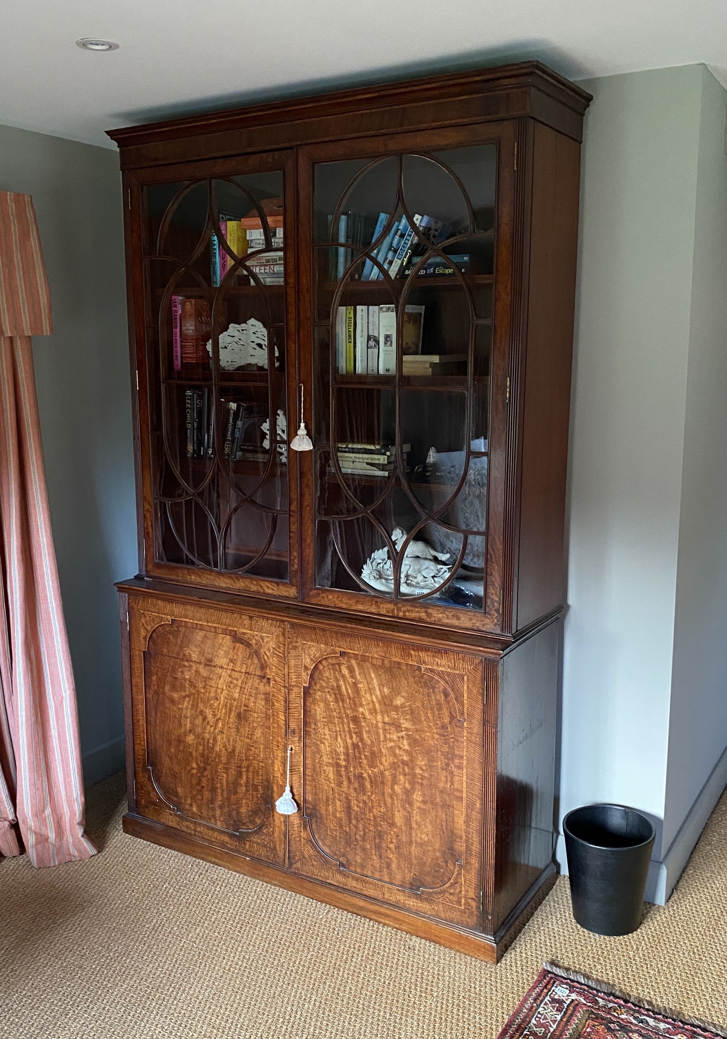 A George III mahogany bookcase, with two astragal glazed doors enclosing adjustable shelves over two panelled doors, width 142cm depth 47cm height 236cm